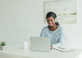 Image of black woman on computer with headphones.